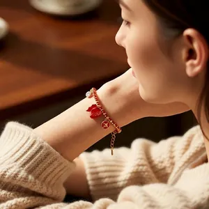 18k gold plated red beaded bracelet with fortune bag and coin charms on a model wrist