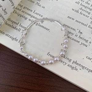 Close-up of elegant pearl and silver wave link bracelet on a fashion book background