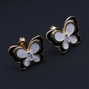 Macro shot of gold butterfly earrings with black and white enamel and zircon stones