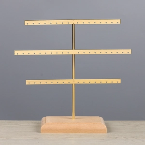 Three-tier gold metal earring stand detail with small holes and solid wood base