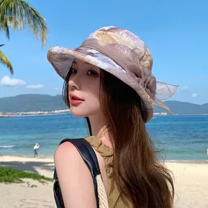 Women's sun protection bucket hat with floral pattern and mesh bow in outdoor beach setting