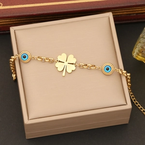 Detail of gold clover bracelet with blue evil eye charms on a jewelry box