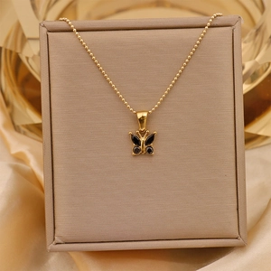 Macro shot of gold butterfly necklace with black zircon in a beige gift box on silk fabric