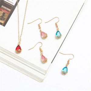 Close-up of teardrop crystal jewelry set including red necklace and pastel earrings