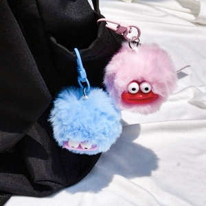 Funny furry monster keychain charms with big eyes and red lips on a black bag
