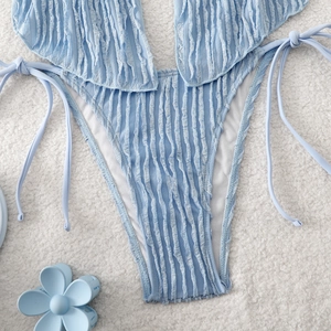 Détail de bikini bleu clair en tissu gaufré avec liens latéraux et accessoire floral