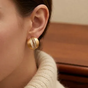 Minimalist gold C-shaped zircon earrings shown on ear with elegant matte satin finish