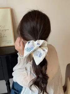 Detail of embroidered jellyfish and seashells on cream oversized satin bow hair tie