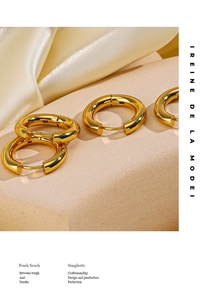 Macro shot of 18K gold plated thick hoop earrings on a neutral stone and silk base