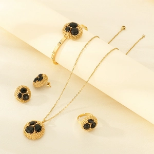 Golden jewelry set with black round stones featuring necklace, bracelet and ring details