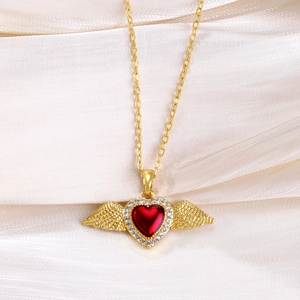 Macro detail of gold-plated necklace with red heart gemstone and zircon wings