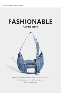 Close-up of blue denim crescent bag with metal eyelets and daily essentials label