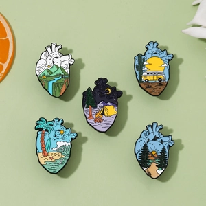Detailed view of five heart-shaped enamel pins featuring nature and travel landscapes
