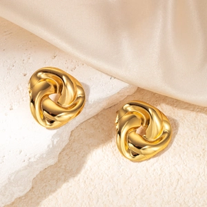 Polished gold-tone twisted knot stud earrings displayed on elegant white stone and silk