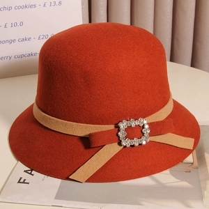 Détail du chapeau cloche en laine orange avec ruban et boucle en strass élégante