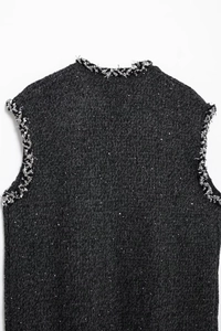 Détail du gilet en tweed tissé foncé avec des paillettes et des finitions à bords effilochés