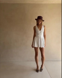 Close-up of the white V-neck sleeveless mini dress featuring front lace-up tie design