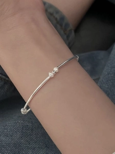 Detail of S925 sterling silver tube bracelet with pearls worn against denim fabric