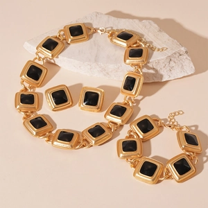 Vintage gold square geometric jewelry set with black enamel inlay on stone background