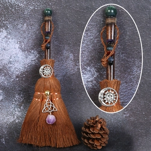 Close-up of witch broom with natural crystal, solar charms and celtic knot on dark wood