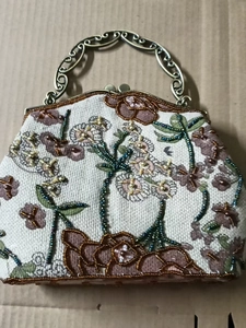 Macro shot of vintage linen handbag featuring intricate bead embroidery and bronze handle