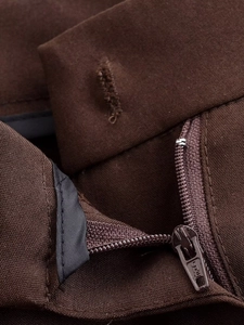 Dettaglio macro dei pantaloni marroni a vita alta con cerniera in metallo e cuciture