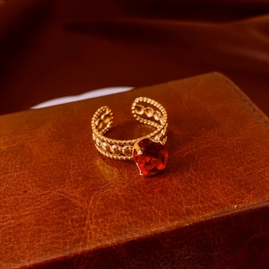 Macro shot of vintage gold-plated ring with red oval gemstone on brown leather background