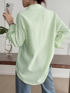 Rear view of a light green striped long sleeve shirt on model in a stylish indoor setting