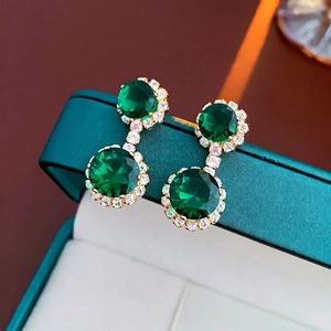 Détail de boucles d'oreilles vintage en gemme verte taille émeraude avec monture dorée