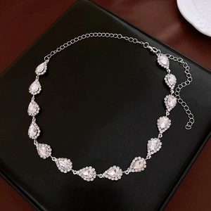 Macro view of water drop crystal necklace with diamond settings on black leather stand