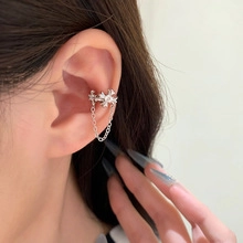 Close-up of silver star ear cuff with chain and crystal detail on female ear