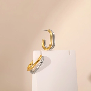 Detail of two-tone gold and silver twisted U-shaped earrings on jewelry display stand