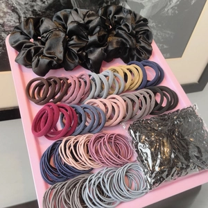 Variety hair accessories set with black silk scrunchies and rubber bands on pink tray