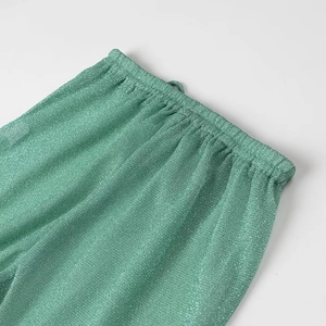 Détail du pantalon vert scintillant avec taille élastique et cordon de serrage