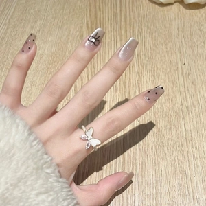 Detail of nude press-on nails with cat eye effect, black bows and polka dot patterns