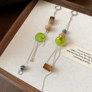 Detail view of retro ethnic style beaded tassel earrings with green and amber stones