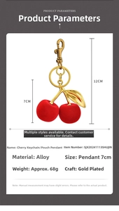 Macro detail of red flocked cherry bag charm with golden alloy leaves and clasp