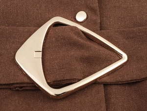 Close-up of golden metallic belt buckle on brown linen textured maxi dress