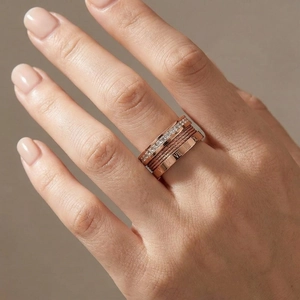 Detailed view of layered rose gold rings with roman numerals and zircon inlay