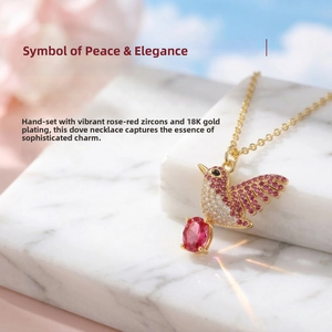 Detail of 18K gold-plated dove pendant with zircon inlay and a large red gemstone