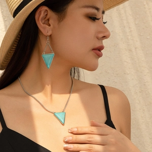 Close-up of turquoise triangle necklace and earrings set worn by a model