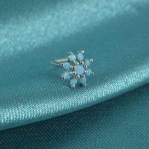 Macro view of snowflake nose stud with turquoise stones on dark teal silk fabric