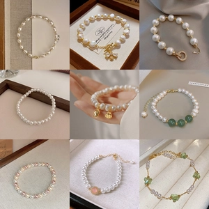 Detail showing a variety of freshwater pearl bracelets with gold pendants and floral charms