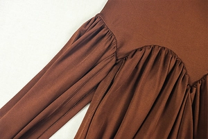 Detail shot of deep brown dress featuring ruched pleats and fine stitching craftsmanship