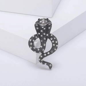 Macro shot of silver cobra brooch featuring sparkling rhinestones and black gem eyes