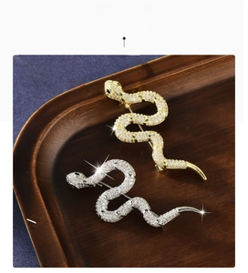 Detailed macro view of snake brooches with gold and silver plating and cubic zirconia