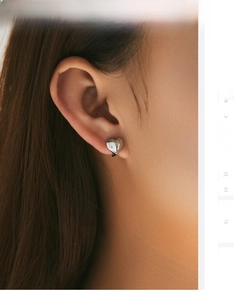 Gros plan d'une boucle d'oreille cœur 3D en argent s925 poli portée par un modèle