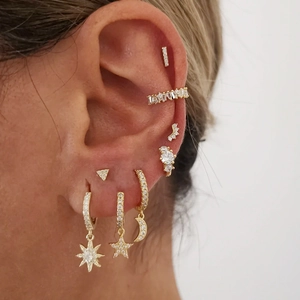 Close-up of gold S925 silver earrings set with sparkling cubic zirconia on a model ear