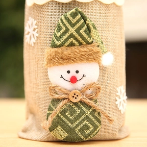 Close-up of burlap Christmas wine bottle bag featuring a snowman with green patterned hat