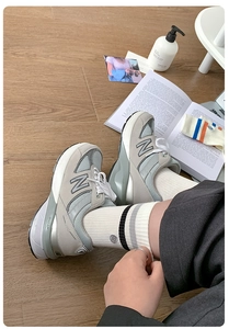 Top view of grey suede sneakers on wooden floor with lifestyle accessories